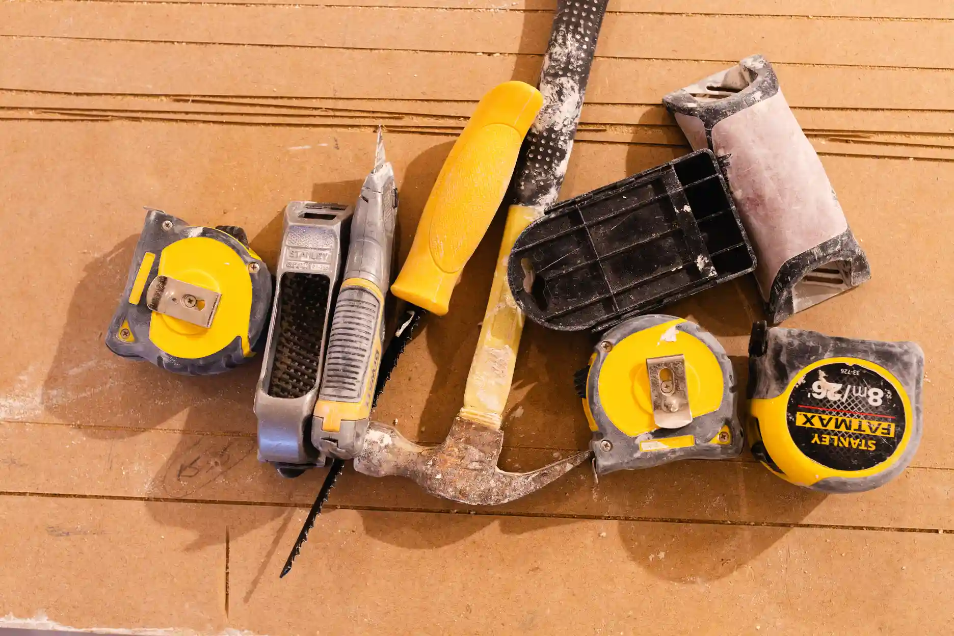 Ren Contractors tools on site in Cornwall: tape measures, hammer, utility knife and sanding block on construction board