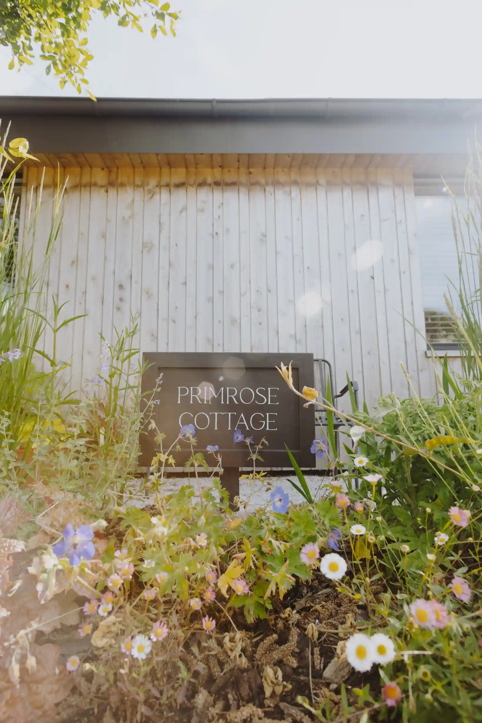Primrose Cottage sign among wildflowers with timber-clad exterior — Ren Contractors & Electrical Cornwall building renovation